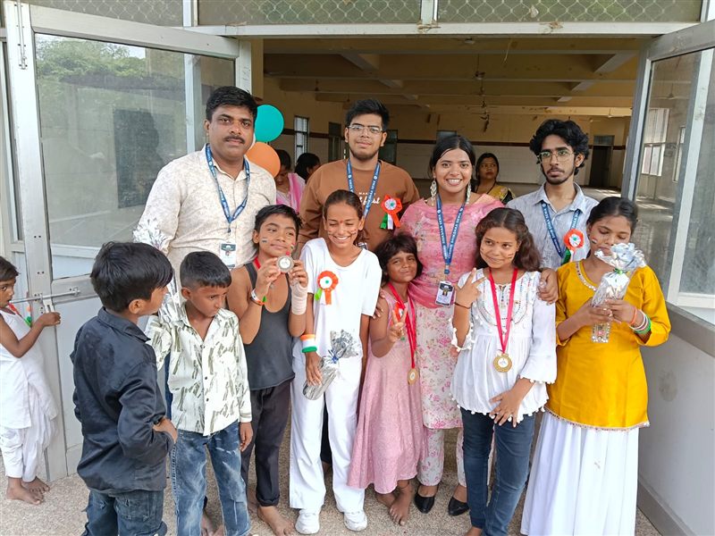 Children wearing prize medals posing with volunteers indoors