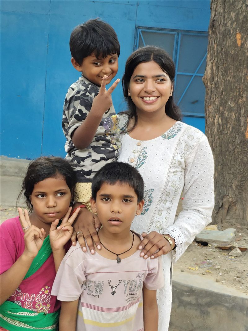 A volunteer posing with three children outdoors