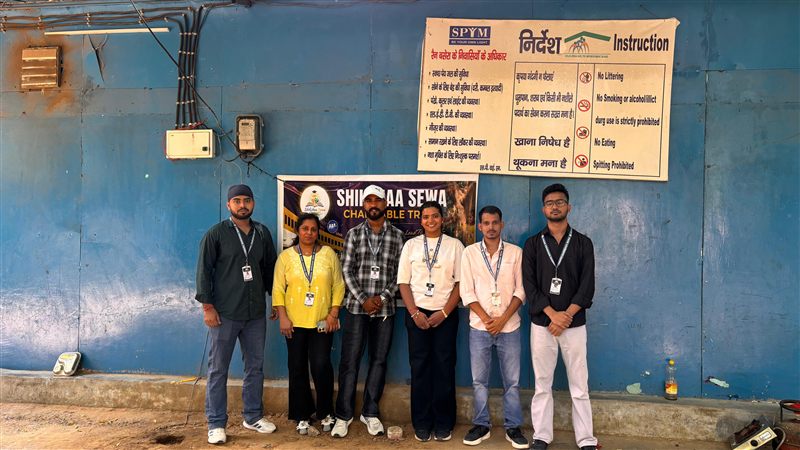 Six volunteers standing in front of a Shikshaa Sewa banner against a blue wall